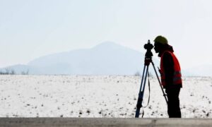 Land surveyor in Kansas performing fieldwork to support a flood elevation certificate for real estate or insurance compliance.