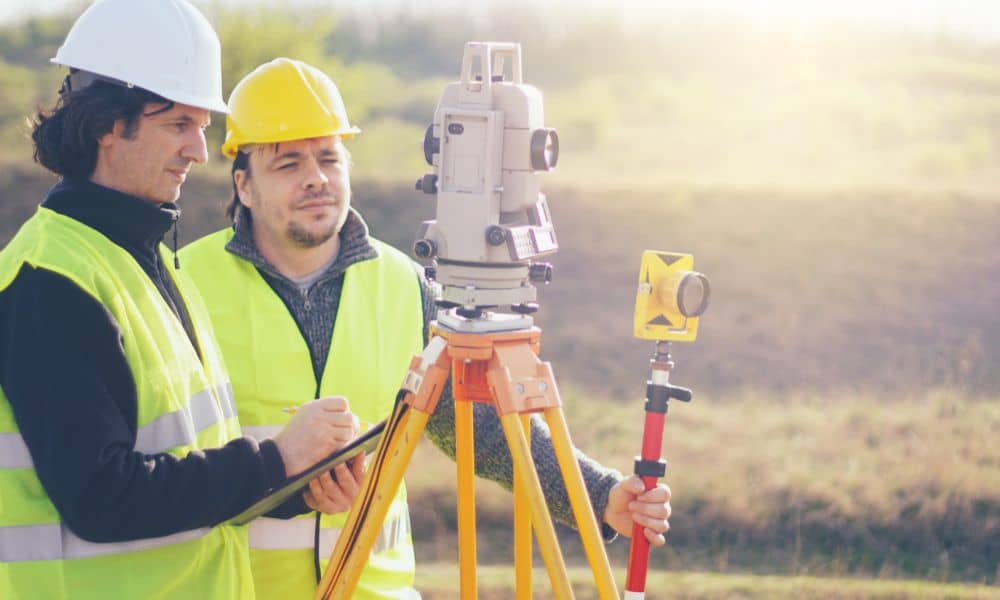 Professional surveyors using a total station to perform an ALTA survey on undeveloped property for a real estate transaction