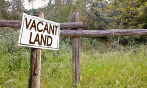 Vacant land with a wooden fence representing the need for a perc test before building