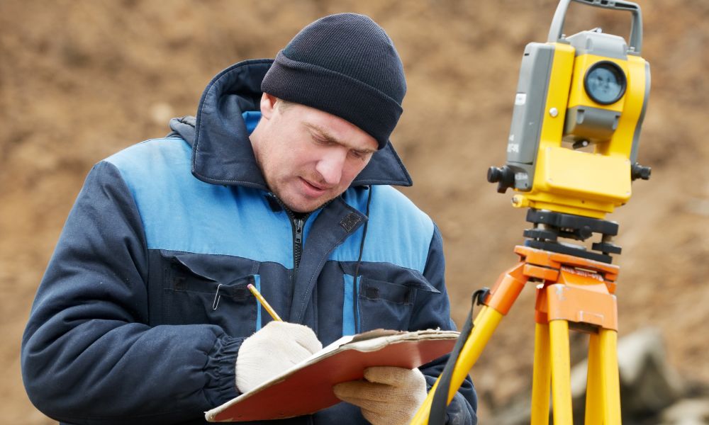Land surveyor using a total station and reviewing records for an ALTA Land Title Survey