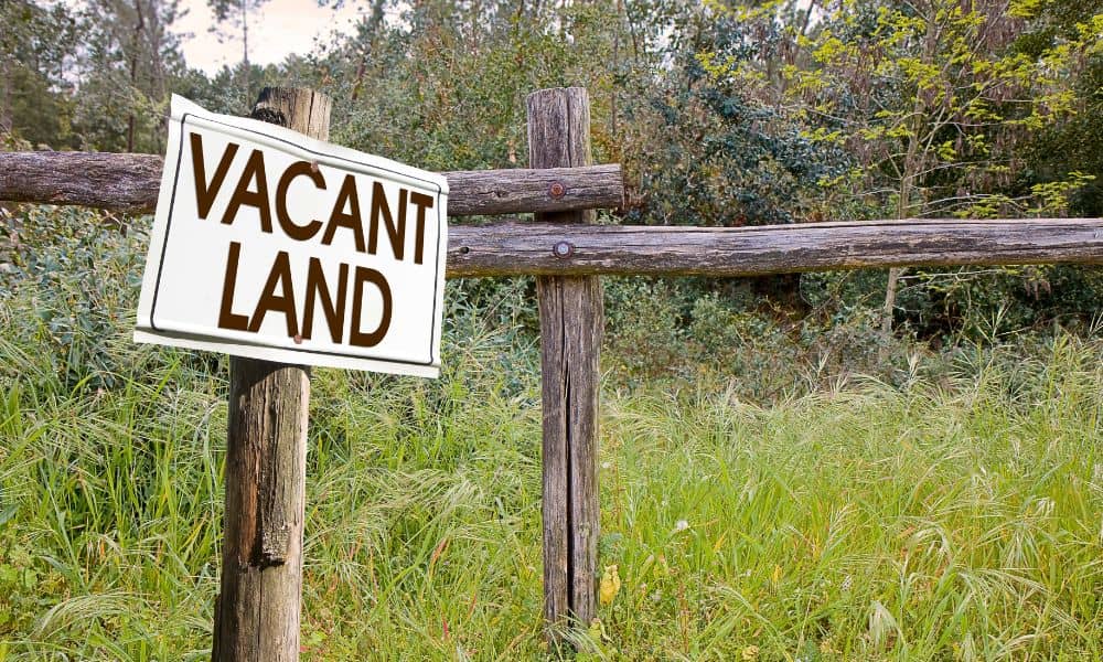 Vacant land with a wooden fence representing the need for a perc test before building

