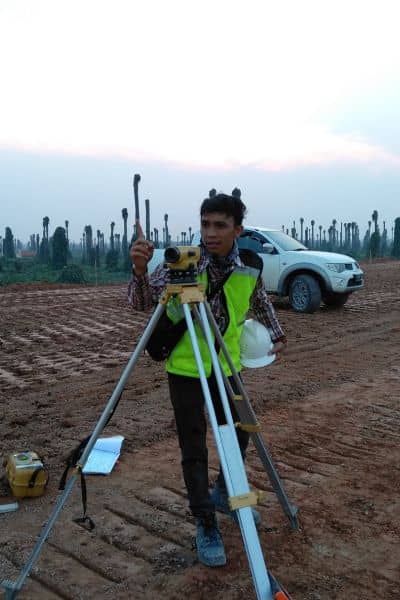  Licensed land surveyor using surveying equipment to mark property boundaries on a development site
