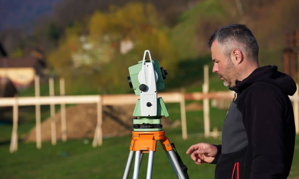 Elevation surveyor on site documenting land measurements - ALTA SURVEY Missouri Land surveyor using a total station during an elevation survey to record precise land measurements for documentation