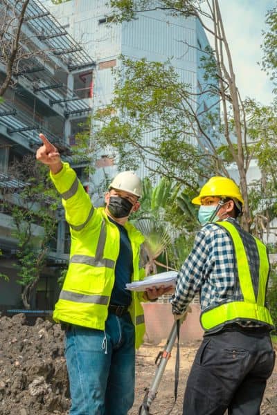 Surveyors reviewing elevation survey data on construction site - ALTA SURVEY Missouri Two surveyors reviewing elevation survey data and site documents to ensure accurate field documentation during construction