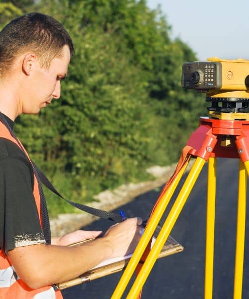 A land surveyor measuring a site with professional equipment, showing how a property survey helps confirm accurate boundaries