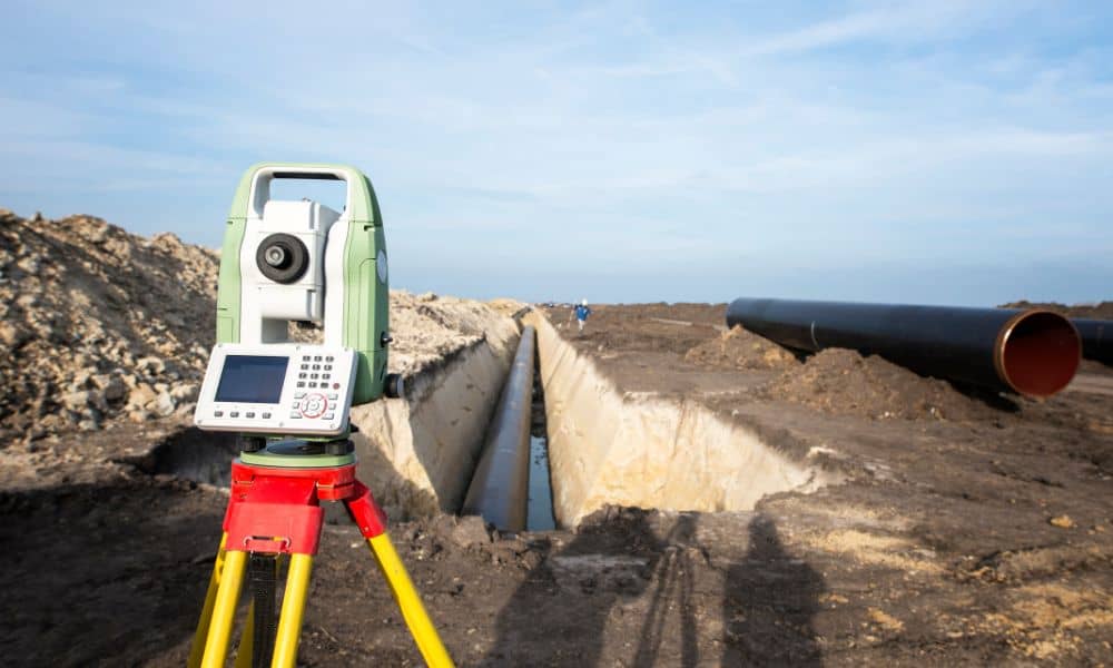 A licensed surveyor using professional equipment to collect data for a FEMA Elevation Certificate during a field measurement