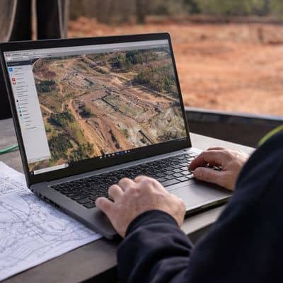 Surveyor reviewing drone surveying data and site imagery on a laptop during project planning