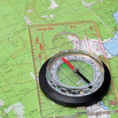Compass and contour map used during a topographic survey to analyze elevation and ground slope