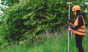 Surveyor collecting measurements for an elevation certificate at a property site