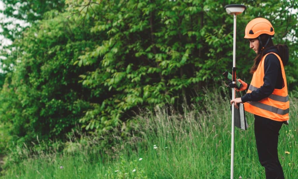 Field surveyor collecting site elevation data - ALTA SURVEY Missouri Surveyor collecting measurements for an elevation certificate at a property site