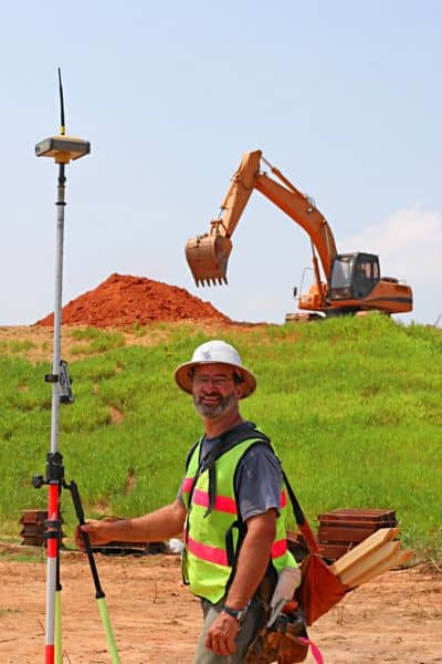 Land surveyor using GPS equipment on a property to collect data for survey mapping and site measurements