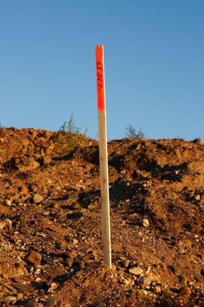 Surveyor marking property boundary lines on-site to confirm land conditions before construction approval