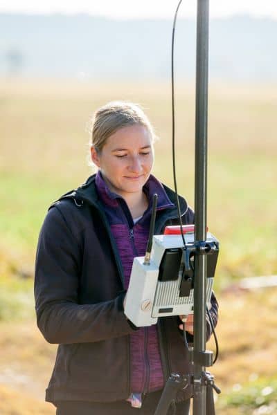 Surveyor using GPS equipment to measure land boundaries and verify property details before buyers work with surveying companies